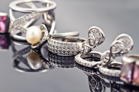 Fine silver rings are together with unusual silver chain on a white acrylic Boardの写真素材