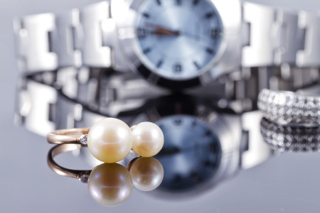 Gold ring with two pearls on the background of chromium-plated women's watchesの写真素材