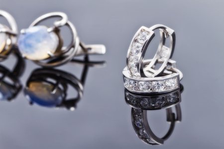 Silver earrings of different sizes and shapes lie in a rowの写真素材