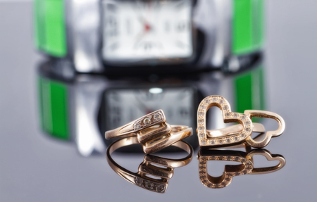 Gold rings of different shapes are on the background of metal women's watchesの写真素材