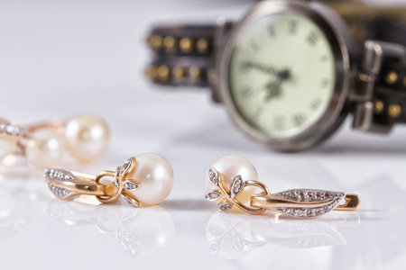 gold jewelry with pearls on a background of elegant women's watchesの写真素材