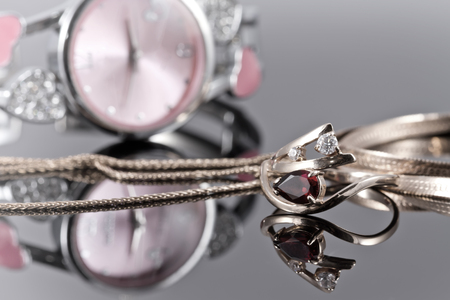 Elegant Golden ring with a ruby and gold chain on the background of pink clocks.の写真素材
