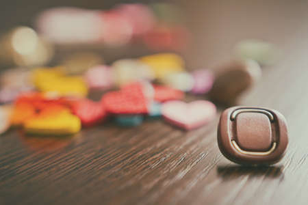 Buttons for garments of different shapes and colors lying on a wooden oak table