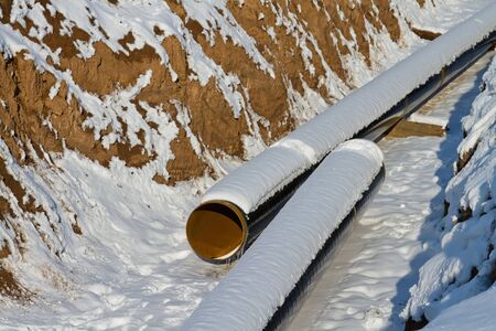 Pipeline laying in polymeric insulation in a trench dug in the winter and covered with snowの写真素材