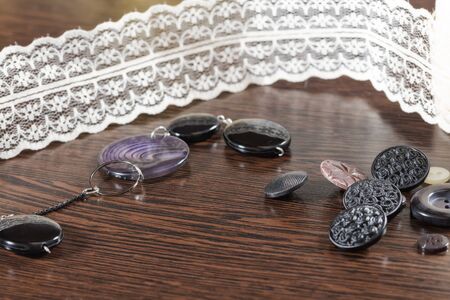 Buttons for garments of different shapes and colors lying on a wooden oak tableの写真素材