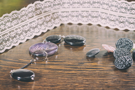 Buttons of different shapes and colors lying on a dark wooden tableの写真素材