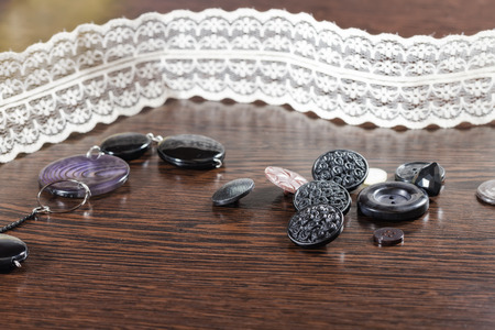 Buttons of different shapes and colors lying on a dark wooden tableの写真素材