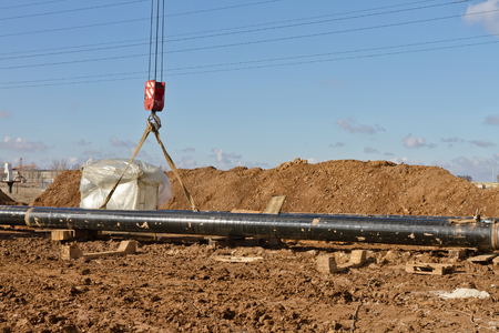 laying of gas main in a trench dug in the field near the power line.の写真素材