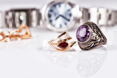 Gold earrings and rings with red rubies lie on the background of the unusual women's watchesの写真素材