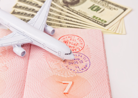 Sketch on vacations and travel: Toy airplane lands on an open passport and dollarsの写真素材