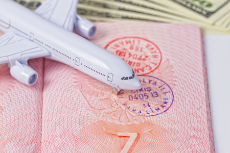 Sketch on vacations and travel: Toy airplane lands on an open passport and dollarsの写真素材