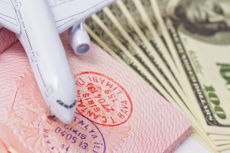 Sketch on vacations and travel: Toy airplane lands on an open passport and dollarsの写真素材