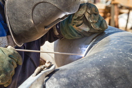 welder performs welding works on pipelines stainless steel