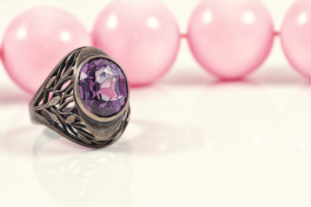 Vintage silver ring with a large amethyst on a background of pink beads with large beadsの写真素材