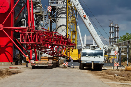 VOLGOGRAD - APRIL 28: Unloading sections of the boom of a large crawler crane using a crane on site of a petrochemical plant . April 28, 2016 in Volgograd, Russia.のeditorial素材