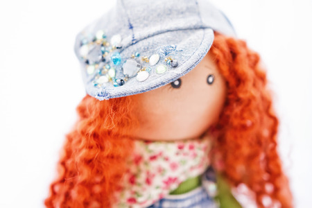 The red-haired handmade doll dressed in a denim clothing in a cap adorned with rhinestonesの写真素材