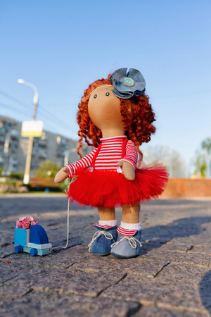 Redhead doll handmade toy car is on the square is paved with cobblestonesの写真素材