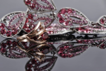 gold ring with a ruby in the background of fashion jewelry with red and pink stonesの写真素材