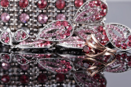 gold ring with a ruby in the background of fashion jewelry with red and pink stonesの写真素材