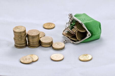 Gold plated coins are in stacks to increase against the background of a simple purse with coinsの写真素材