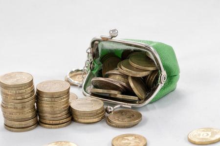 Gold plated coins are in stacks to increase against the background of a simple purse with coinsの写真素材