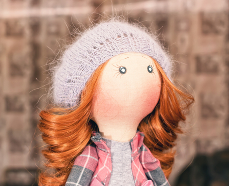 Handmade doll with red hair in a knitted capの写真素材