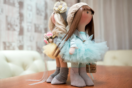 Two handmade rag dolls with natural hair - blonde and brown-haired, in knitted hatsの写真素材