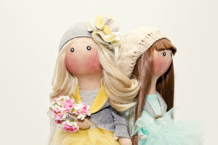Two handmade rag dolls with natural hair - blonde and brown-haired, in knitted hatsの写真素材