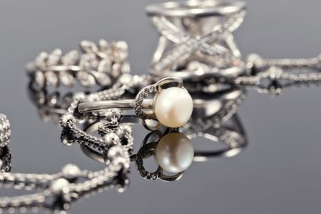 Fine silver rings are together with unusual silver chain on a white acrylic Boardの写真素材