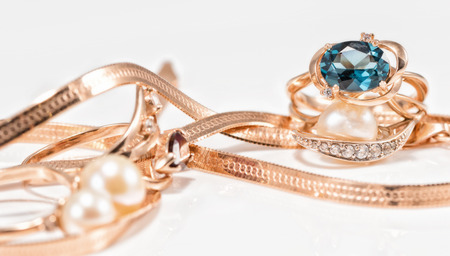 Gold earrings and rings from different sets amid the chain with a snake weavingの写真素材