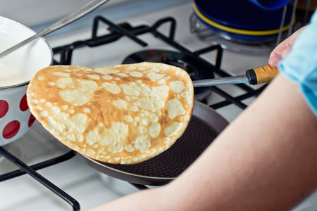 Cooking pancakes on Shrove Tuesday in a special pan in the kitchen at homeの写真素材