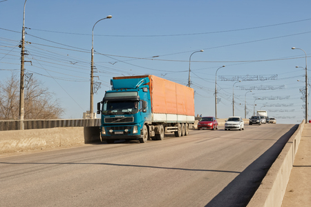 VOLGOGRAD - MARCH 5: Trucks with a trailer under the awning rises up over the bridge in the flow of urban transport. March 5, 2017 in Volgograd, Russia.のeditorial素材