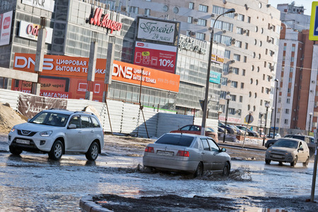 VOLGOGRAD - FEBRUARY 21: Cars cross a huge puddle of dirty water with a depth of half the wheel. February 21, 2017 in Volgograd, Russia.のeditorial素材