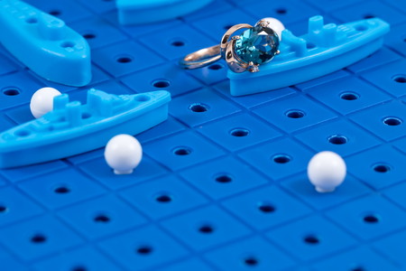 A gold ring lies on the game Board with toy military ships ready for battleの写真素材