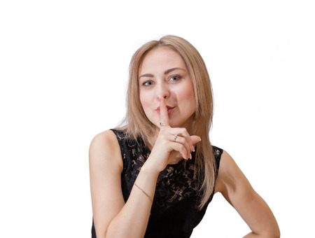 Adorable young blonde shows sign behave quieter . Placing a forefinger to her lipsの写真素材