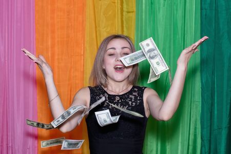 Charming young girl with a slender figure enjoys the falling money in the background of colorful paintingsの写真素材