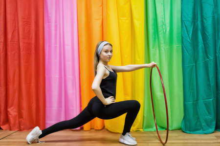 Flexible young woman in sportswear does exercises on an extension with a Hoop in the gymの写真素材
