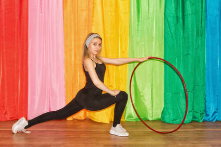 Flexible young woman in sportswear does exercises on an extension with a Hoop in the gymの写真素材