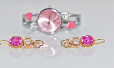 Elegant Golden ring with a ruby and gold chain on the background of pink clocks.の写真素材