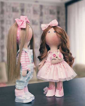 Two handmade rag dolls with natural hair - blonde and brown-haired, in knitted hatsの写真素材