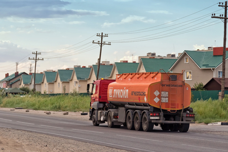 VOLGOGRAD - JULY 30: Truck LUKOIL hauling a fuel tanker past a country cottage settlement. July 22, 2016 in Volgograd, Russia.のeditorial素材