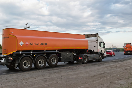VOLGOGRAD - JULY 30: A truck hauling an orange fuel tanker on bypass road. July 22, 2016 in Volgograd, Russia.のeditorial素材