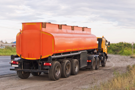 Lorry with orange tanker on parked on the roadside of a rural asphalt roadの写真素材