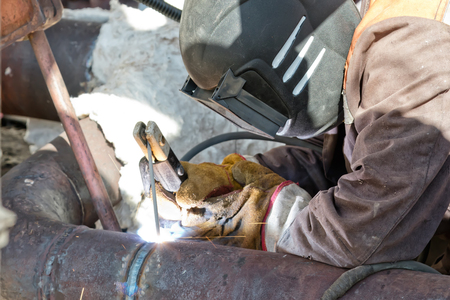 Welder in the mask and protective clothing is gaining increased cladding weldの写真素材
