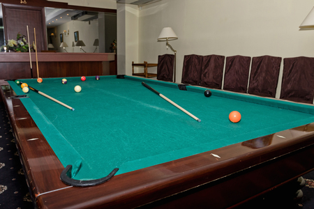Worn pool table with a cue and balls in the great hall of the guests in the restaurantの写真素材