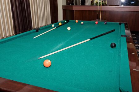 Worn pool table with a cue and balls in the great hall of the guests in the restaurant