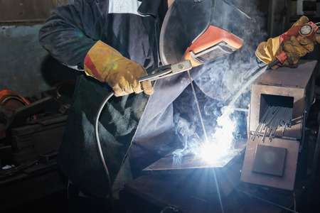 Welder in workshop conditions sample weld from sheet metal to undergo certification. Manual arc welding using remote controlの写真素材
