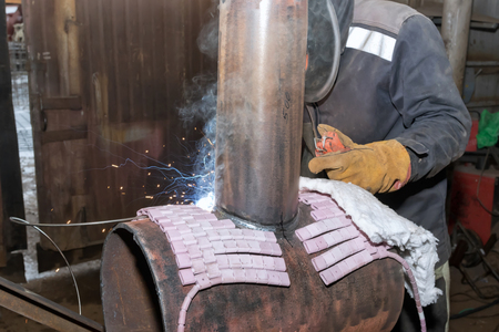 Welder in the shop weld sample from the tube with concomitant heating for attestation. Manual arc welding using remote controlの写真素材