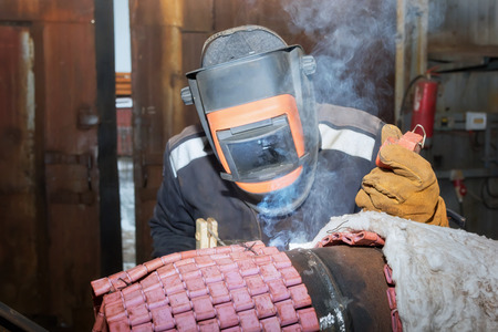 Welder in the shop weld sample from the tube with concomitant heating for attestation. Manual arc welding using remote controlの写真素材