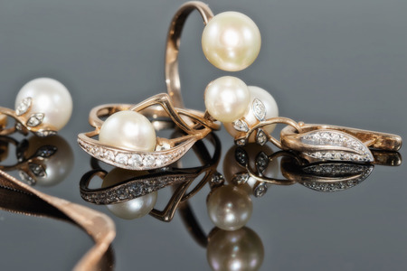 Gift set of gold jewelry with pearls on black reflect surfaceの写真素材